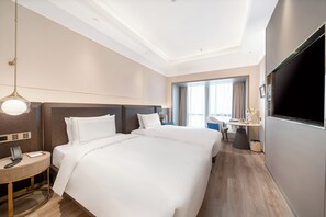 Une chambre d’hôtel avec deux lits, un bureau, une chaise, une télévision et une fenêtre avec des rideaux.