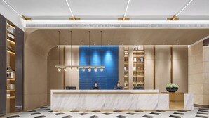 A modern reception area with a marble counter, blue-tiled wall, and a reception desk with two staff members. - Echarm plus International Hotel Guangzhou Changgang Subway Station - Free Shuttle Bus to Canton Fair Complex During Canton Fair Period (Guangzhou)
