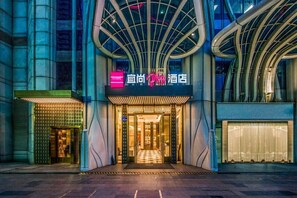 L’entrée d’un hôtel au design moderne, avec une enseigne bien visible et un motif à carreaux sur le sol qui invite à entrer.