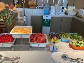 Un buffet proposant une variété d’aliments, notamment des fruits, des légumes et de la viande.