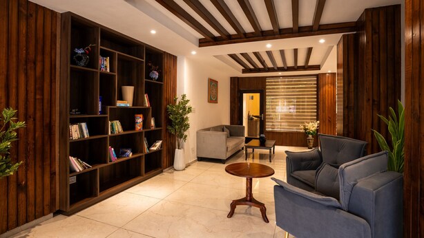 Una sala de estar moderna con una estantería de madera, un sofá gris, una mesa de centro y una ventana con persianas.