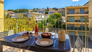 A balcony with a table set for two, overlooking a residential area with buildings and trees. - Les Voiles by Interhome (Six Fours)