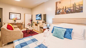 A hotel room with a bed, a desk, a chair, and a dining area. - Precious Florannjoe Chic New Studio With Best Care (Las Pinas)