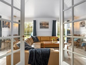 Ein großzügiges Wohnzimmer mit einer großen Eckcouch, einem Couchtisch und Blick durch Glastüren auf einen Außenbereich.