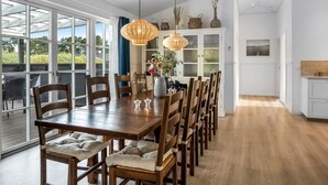 A dining area with a wooden table and chairs, a large window, and a white cabinet with glass doors.