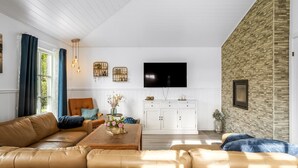 A modern living room with a leather sofa, a wooden coffee table, and a stone accent wall.