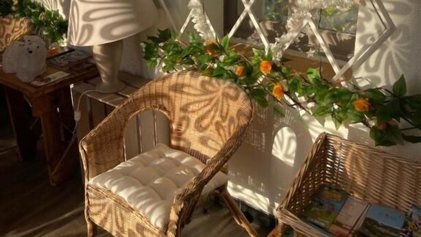 A cozy room with a wicker chair, a small table with a lamp, and a decorative wall with a geometric pattern. - Hotel Clair Logis (Argelès-sur-Mer)
