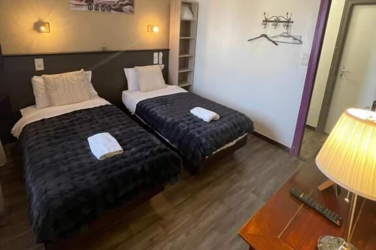 Habitación de hotel con dos camas, un escritorio con lámpara y un armario.