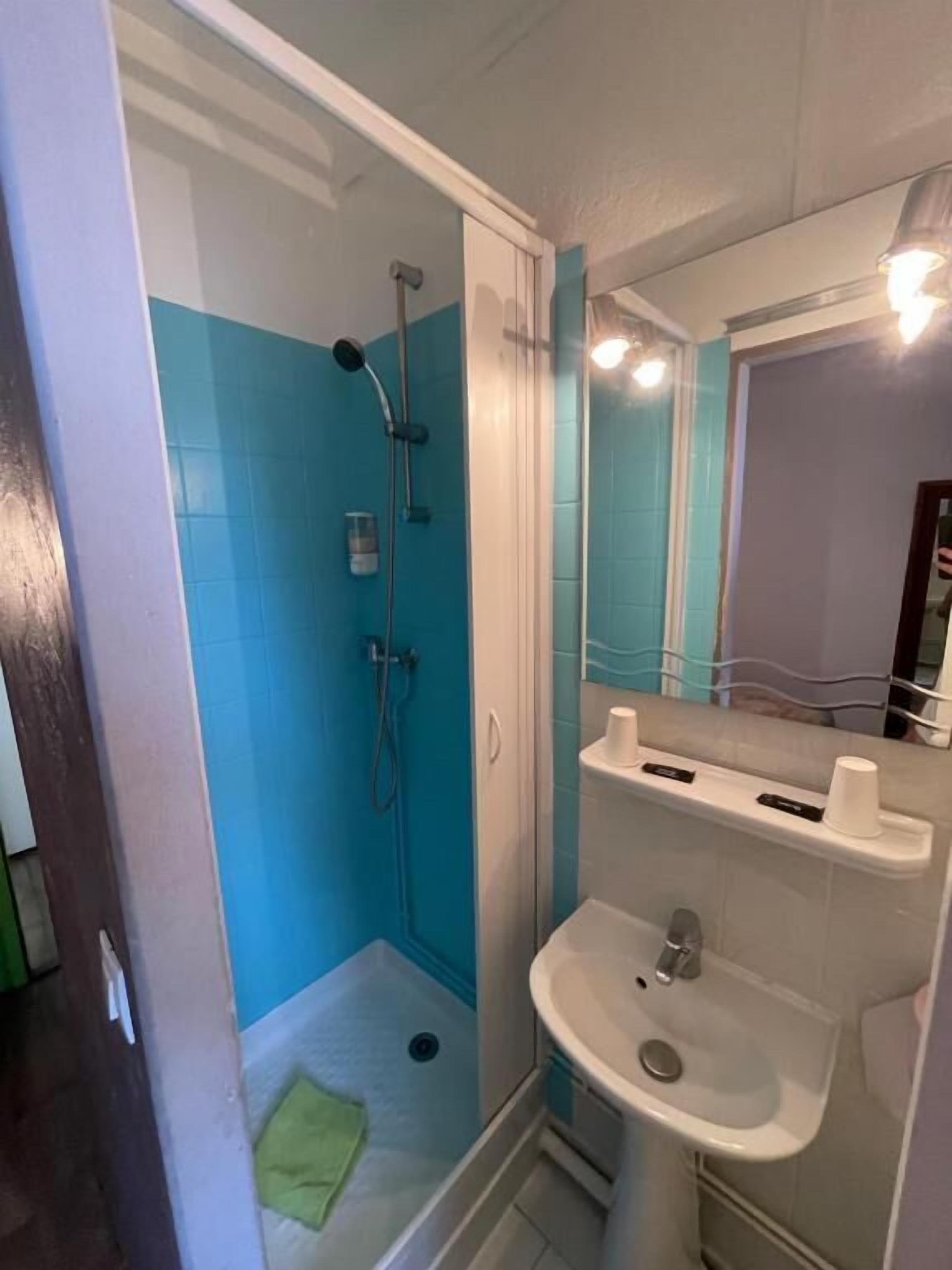 Un baño con ducha, lavamanos y espejo.