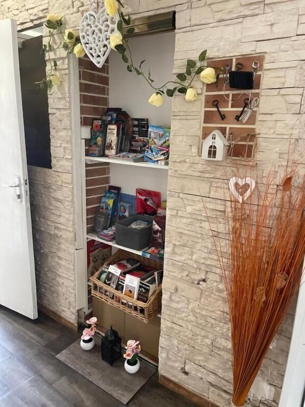 A storage area with shelves containing books, bags, and decorative items. - Hotel Clair Logis (Argelès-sur-Mer)