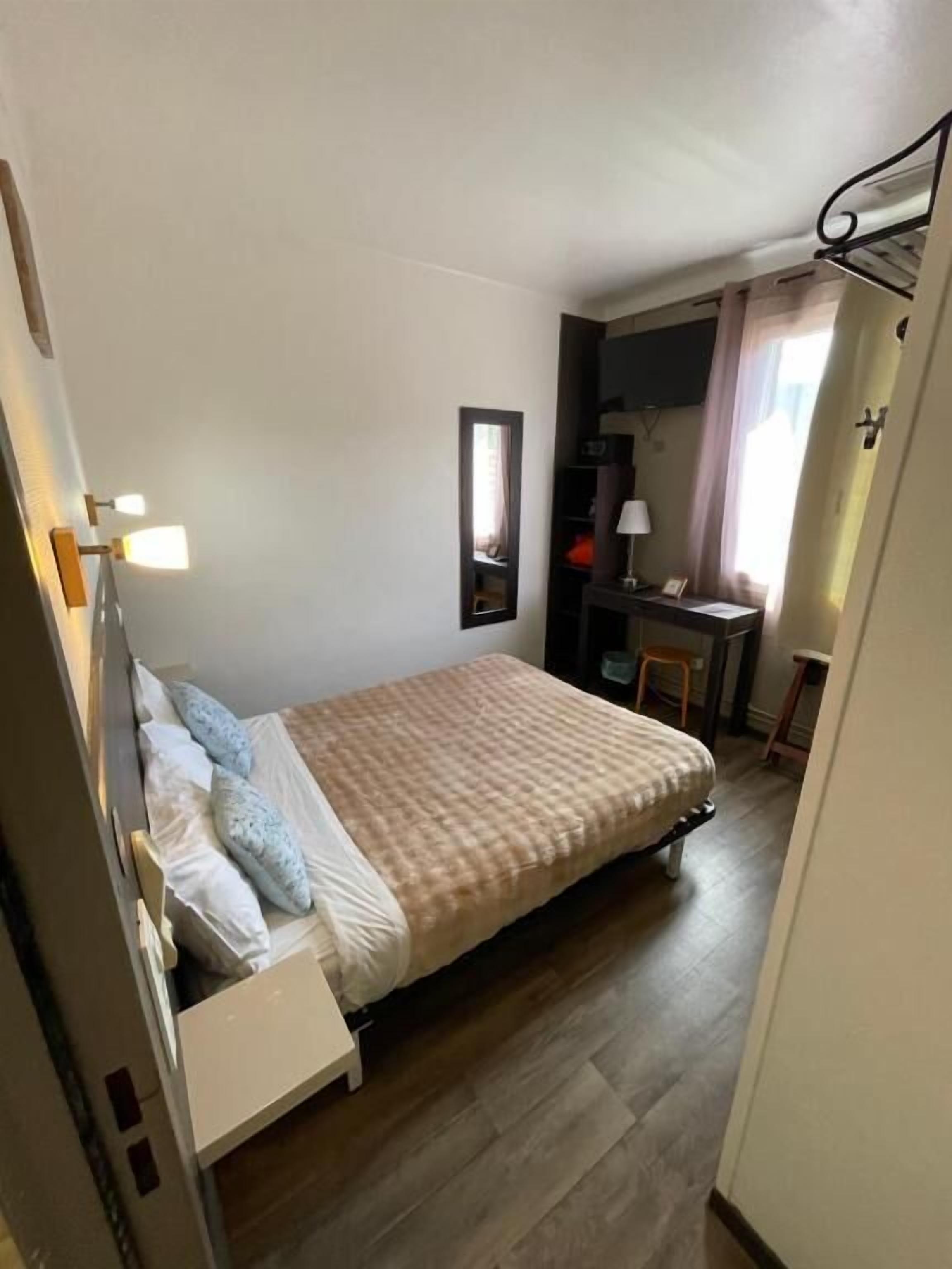 Une petite chambre à coucher, bien rangée, avec un lit, une table de chevet et un bureau avec une chaise.