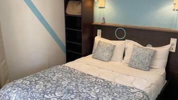 Une chambre à coucher comprenant un lit, une table de chevet, une lampe, un tableau décoratif et une étagère.