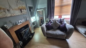 A living room with a fireplace, a sofa, and a mirror. - Lovely 2-bedroom cosy apartment with driveway & garden in charming Dundee (Dundee)
