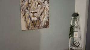 A room with a grey wall, a painting of a lion, a white shelf with plants, and a wooden floor. - Lovely 2-bedroom cosy apartment with driveway & garden in charming Dundee (Dundee)