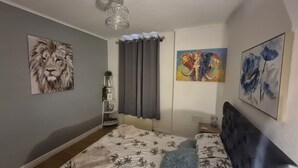 A bedroom with a bed, a nightstand, a lamp, and wall art. - Lovely 2-bedroom cosy apartment with driveway & garden in charming Dundee (Dundee)