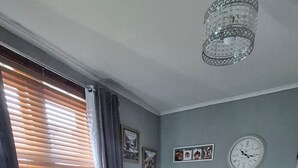 A living room with two grey sofas, a wooden floor, a chandelier, and a clock on the wall. - Lovely 2-bedroom cosy apartment with driveway & garden in charming Dundee (Dundee)