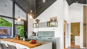 A modern kitchen with a central island, bar stools, and a view of the outdoors.