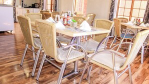 Zona pranzo con sedie in vimini e un tavolo di legno, corredata di tovaglioli e condimenti.