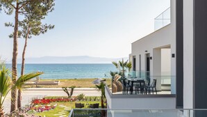 Un edificio moderno con balcón que da a un jardín ajardinado y al mar.