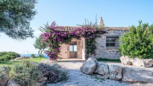 A stone house with a gravel driveway, a large rock garden, and a view of the sea. - Stazzo Serafini by Interhome (Rena Majore)
