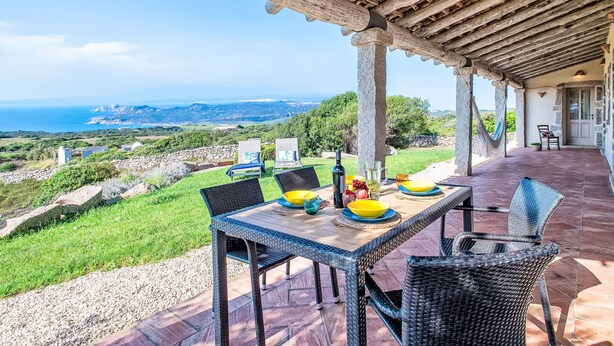 A covered outdoor dining area with a table set for two, overlooking a scenic landscape with the sea in the distance. - Stazzo Serafini by Interhome (Rena Majore)