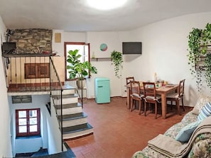 A living room with a staircase, a dining area, and a kitchen.
