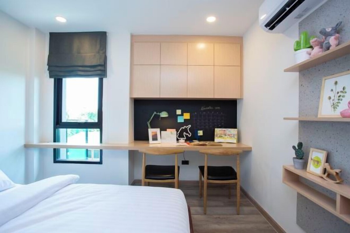 A modern bedroom with a bed, a desk with a computer, and a chalkboard.