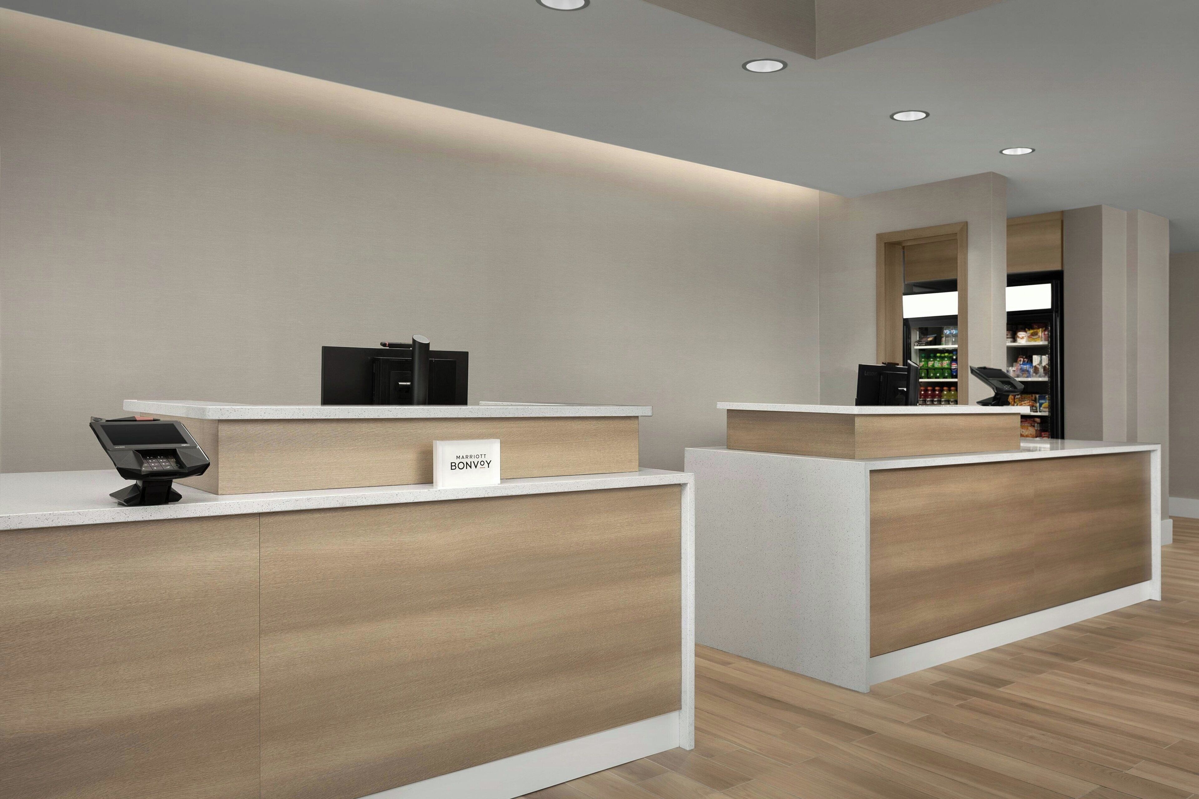 Zona de recepción de un hotel con diseño moderno, que incluye un mostrador de recepción, una terminal de check-in digital y el logotipo visible de Marriott Bonvoy.