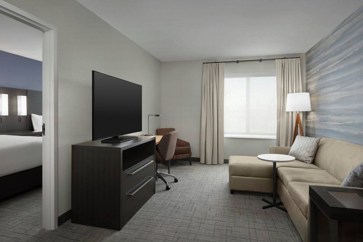 Une chambre d’hôtel comprenant un lit, un bureau avec une télévision, un canapé, une petite table ronde et une lampe.