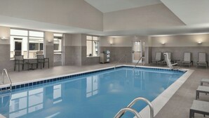 A modern indoor swimming pool with clear blue water, surrounded by lounge chairs and a sunlit patio area. - Residence INN BY Marriott Dayton Miamisb (Miamisburg)