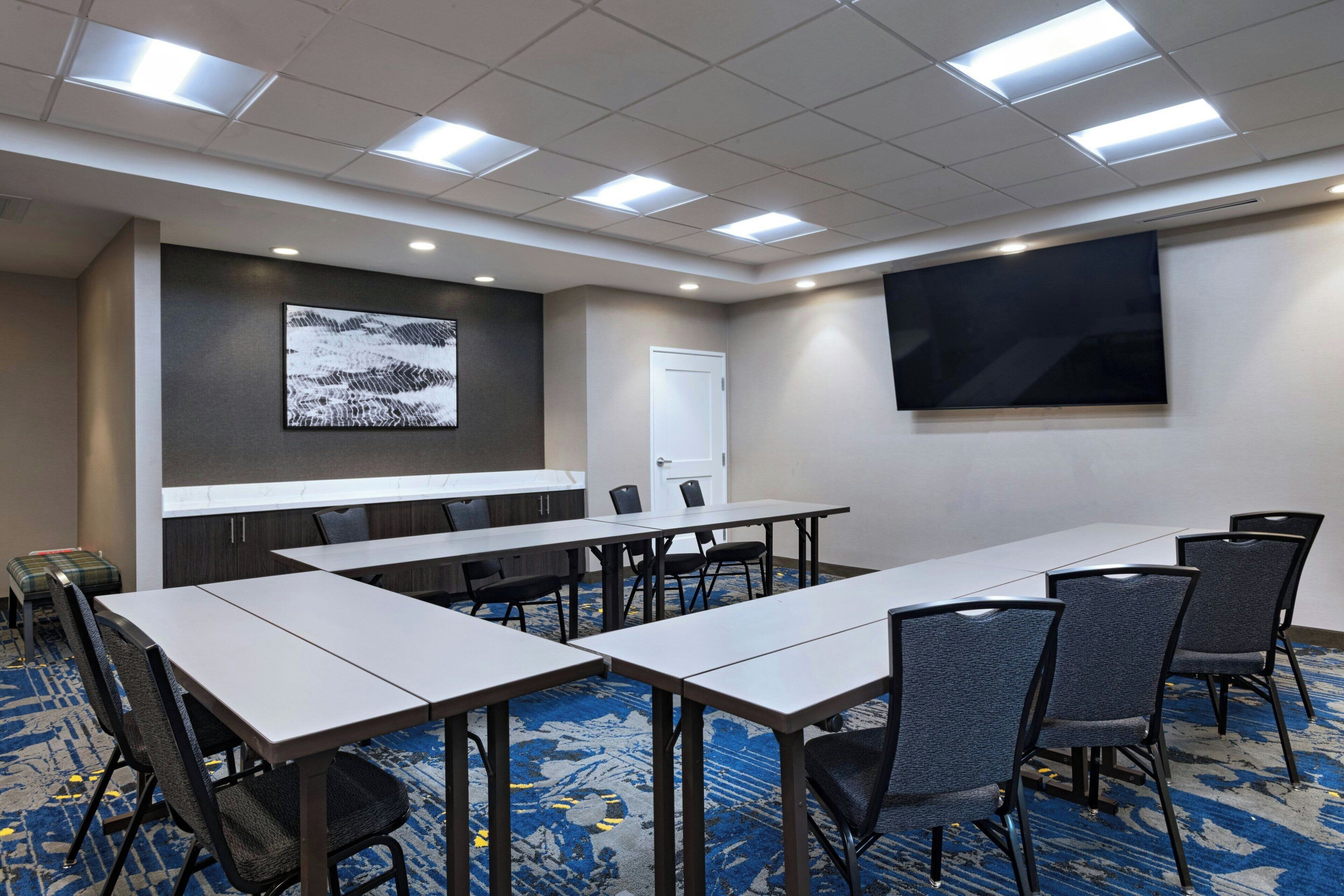 A conference room with a long table, chairs, a projector screen, and a whiteboard.
