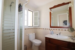 Un baño con ducha, inodoro, lavamanos y espejo.