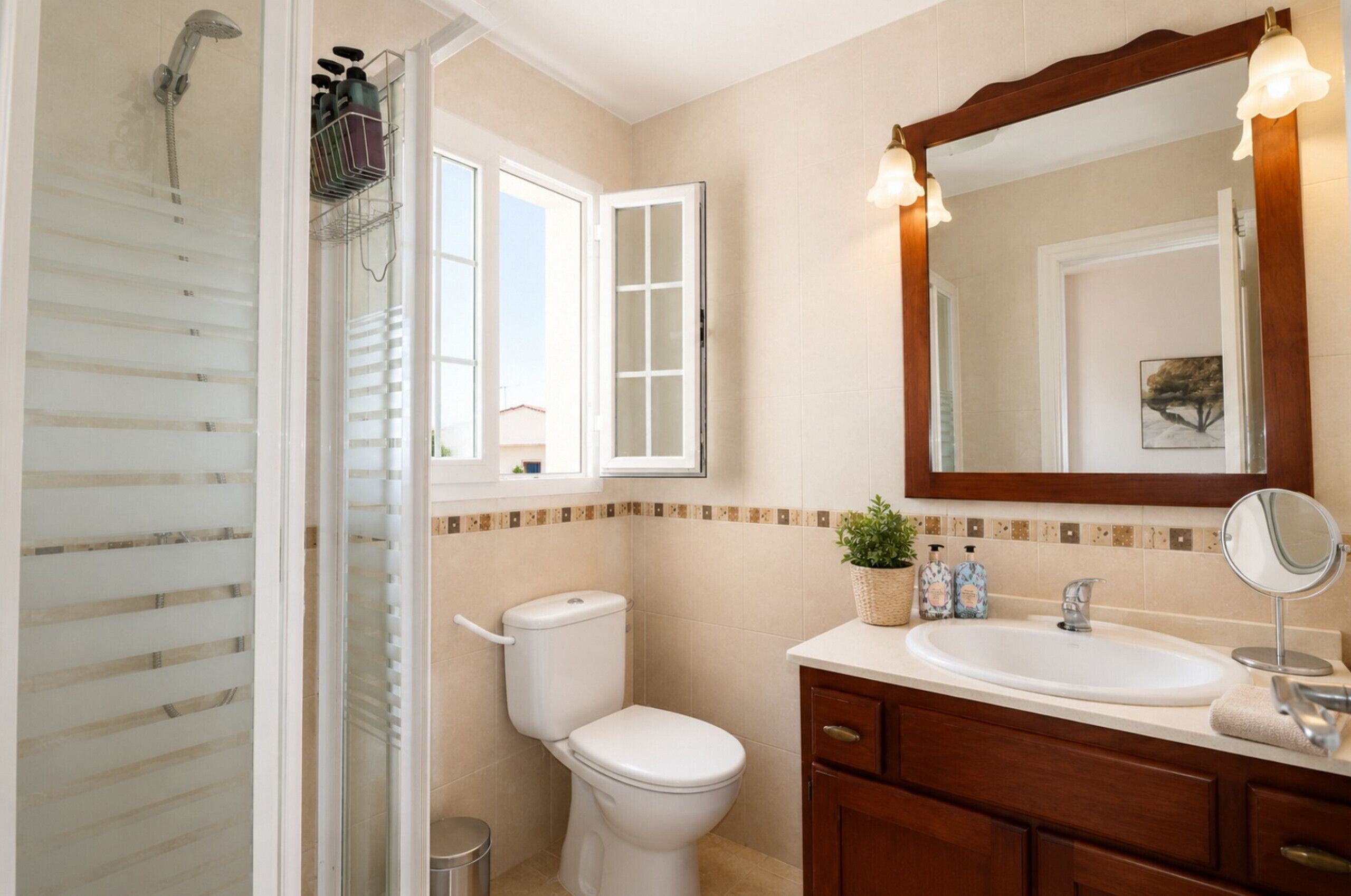 A bathroom with a shower, toilet, sink, and a mirror.