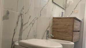 A modern bathroom with a marble backsplash, a wooden vanity, and a white toilet. - Melly House: fast Wi-Fi, 5 minutes from the sea (Barletta)