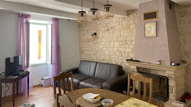 Una sala de estar con pared de piedra, chimenea, sofá de cuero, mesa de comedor y televisor.