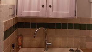Una cocina con armarios blancos, un lavamanos doble y un salpicadero de azulejos.