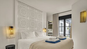 A hotel room with a large bed, a decorative wall, a window with curtains, and a bedside table. - Casa Azalia (Marbella)