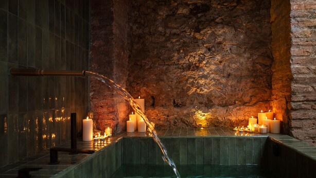 A spa area with a stone wall, a hot tub, and candles. - Casa Azalia (Marbella)