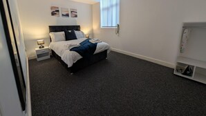 A bedroom with a bed, bedside tables, a window, and a wardrobe. - Broad Street, Wolverhampton - 2 Bedroom Apartment (Wolverhampton)
