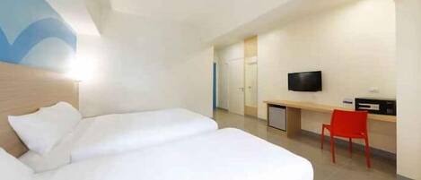 A hotel room with two beds, a desk, a TV, and a red chair.