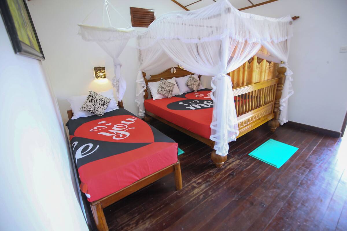 A room with two beds, each with a canopy bed and a red mattress.
