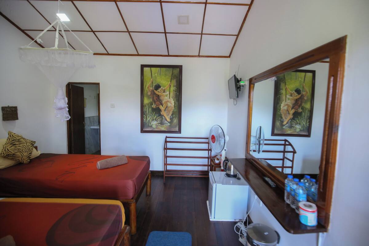 A room with two beds, a desk, a mirror, and artwork on the walls.