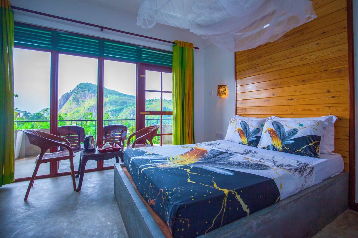 A bedroom with a bed, a chair, and a view of a mountain.