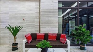 Eine moderne Lobby mit einer Couch, zwei Kübelpflanzen und einem Couchtisch.