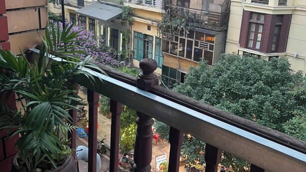 A balcony with a view of a cityscape, including buildings and a street with outdoor seating. - Asia Cozy House (Hanoi)
