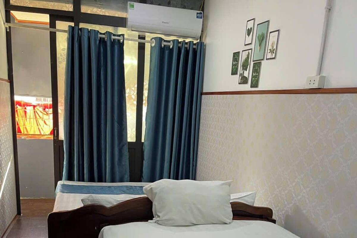 Una habitación de hotel con una cama, un banco de madera y una ventana con cortinas azules.