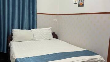 A bedroom with a bed, a wooden headboard, a nightstand, and a wall with framed pictures.