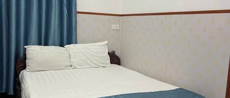 A bedroom with a bed, a wooden headboard, a nightstand, and a wall with framed pictures.