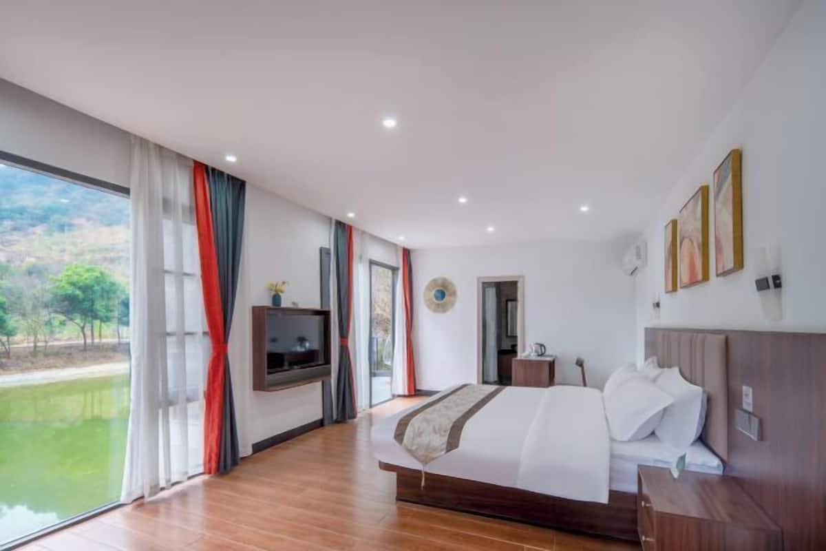 Un dormitorio amplio con una cama grande, televisión y vistas a un lago.