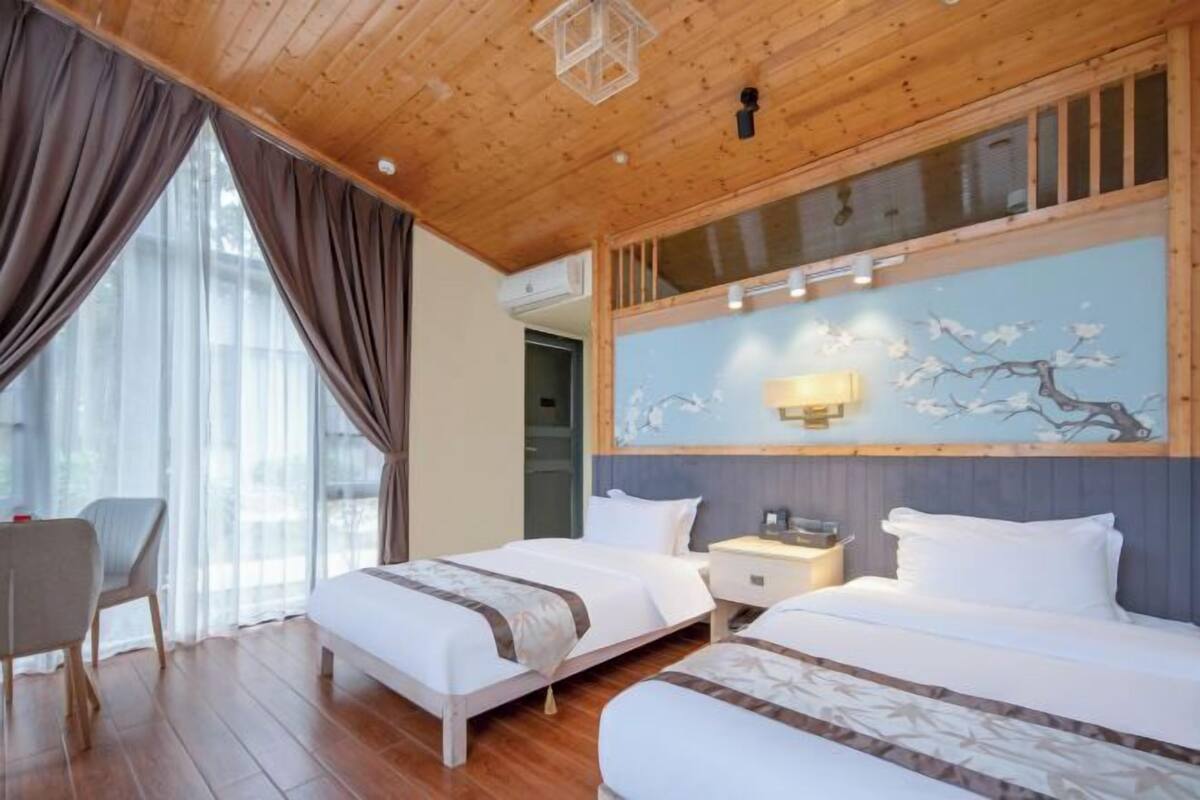 Habitación de hotel con dos camas, techo de madera, un cuadro en la pared y un escritorio con una silla.